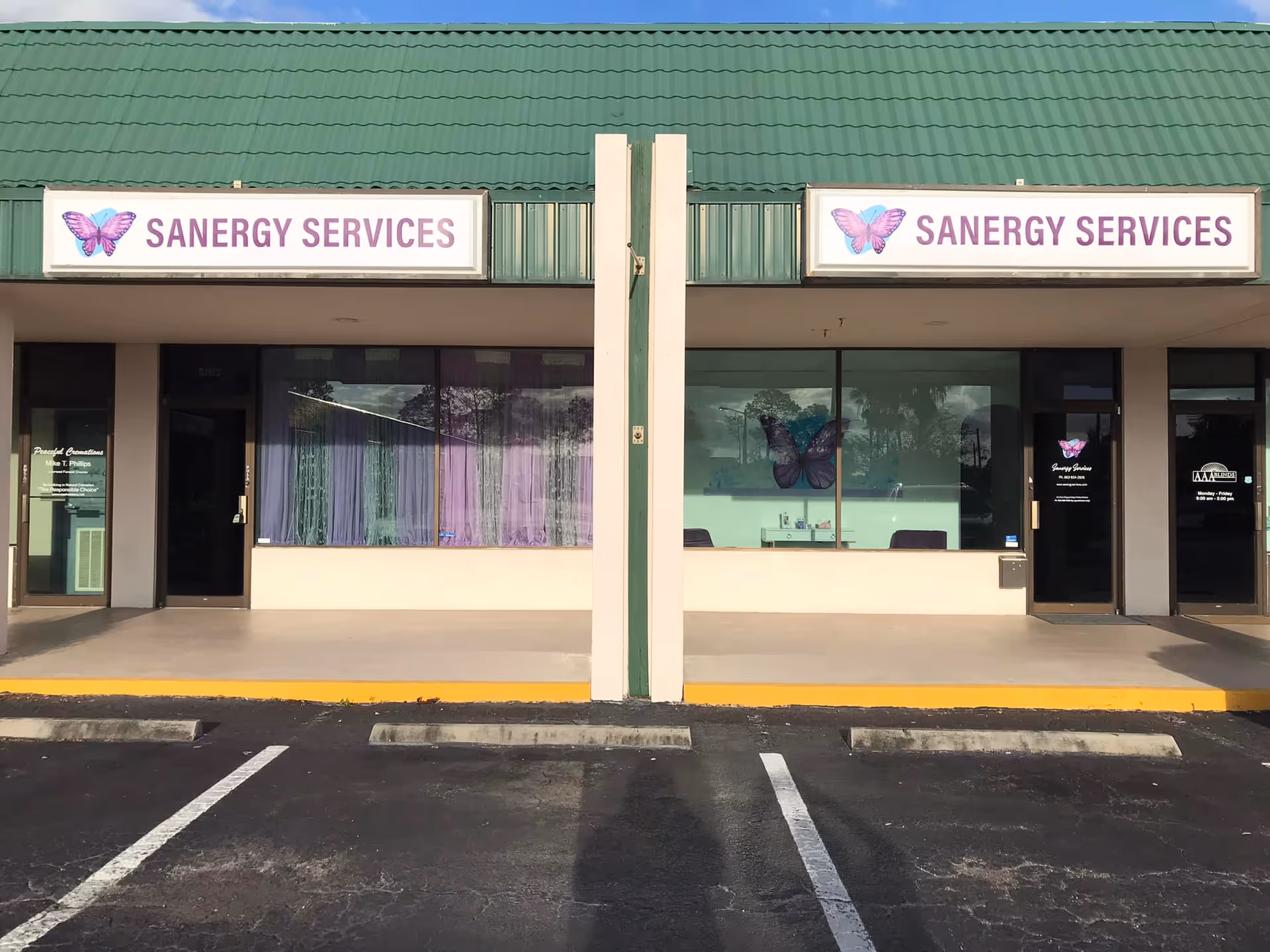 Front exterior of a building with two Sanergy Services signs and a green roof.