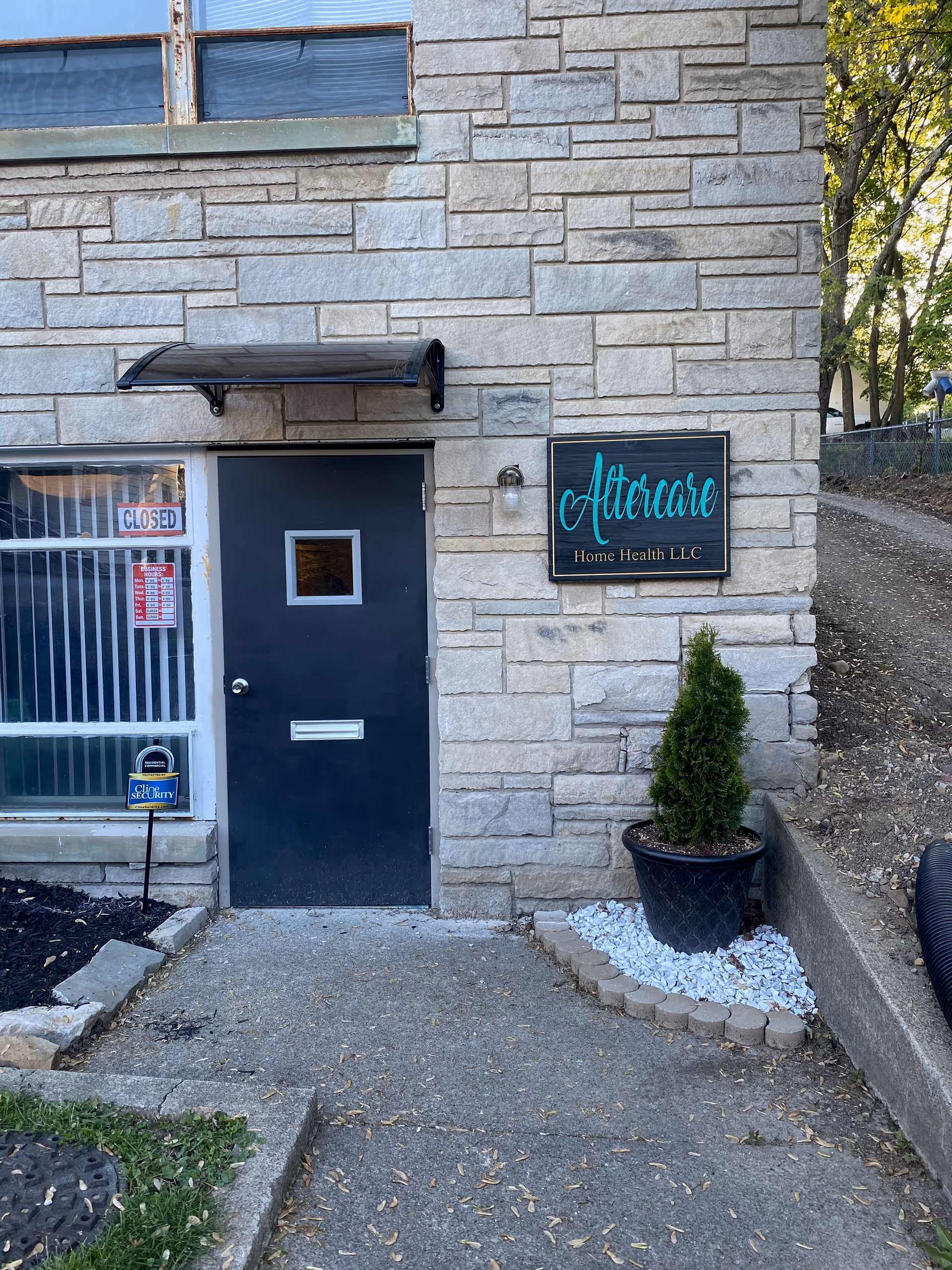 Exterior view of Altercare Home Health LLC entrance with stone walls and a potted plant.