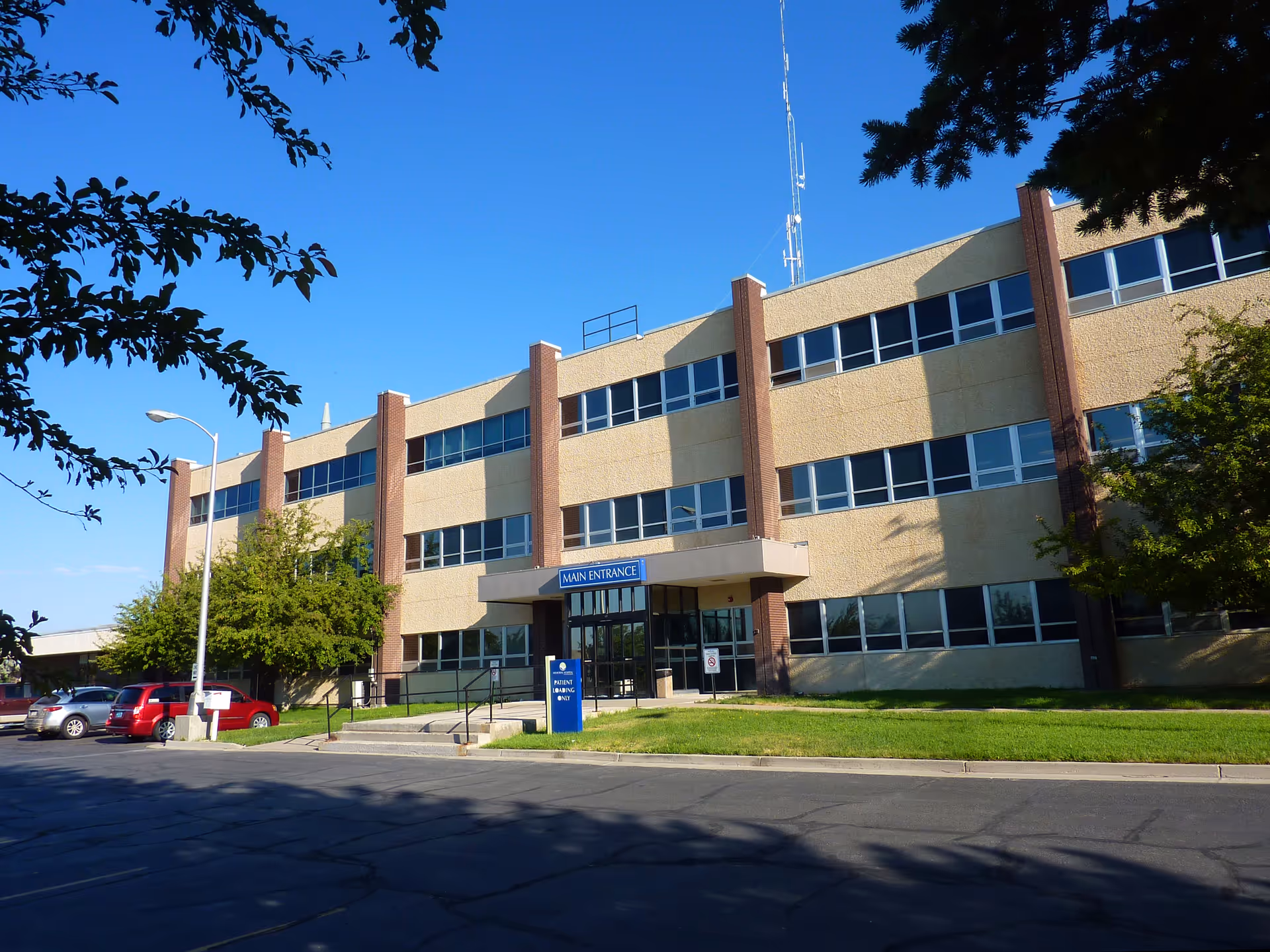 Exterior view of a three-story beige building with blue windows and a main entrance.