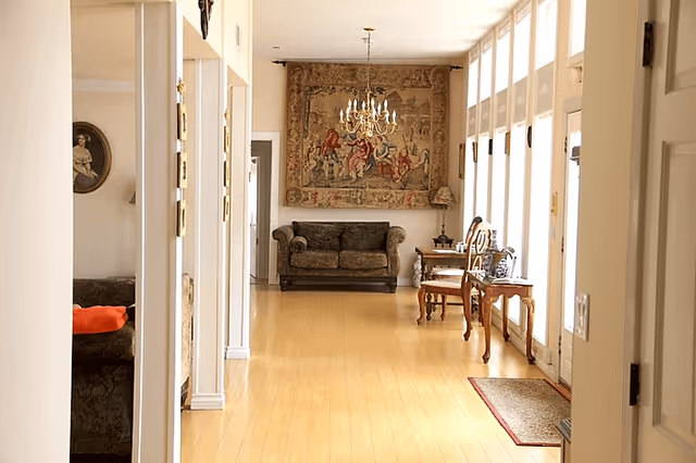 Bright hallway in a senior living facility with a couch, chairs, and ornate tapestry.