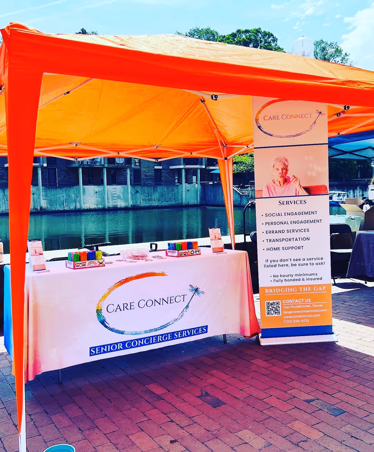 Outdoor orange tent with Care Connect banner and services display near the water.