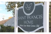 A Saint Francis Home sign with slogan and a fence in front of a building.