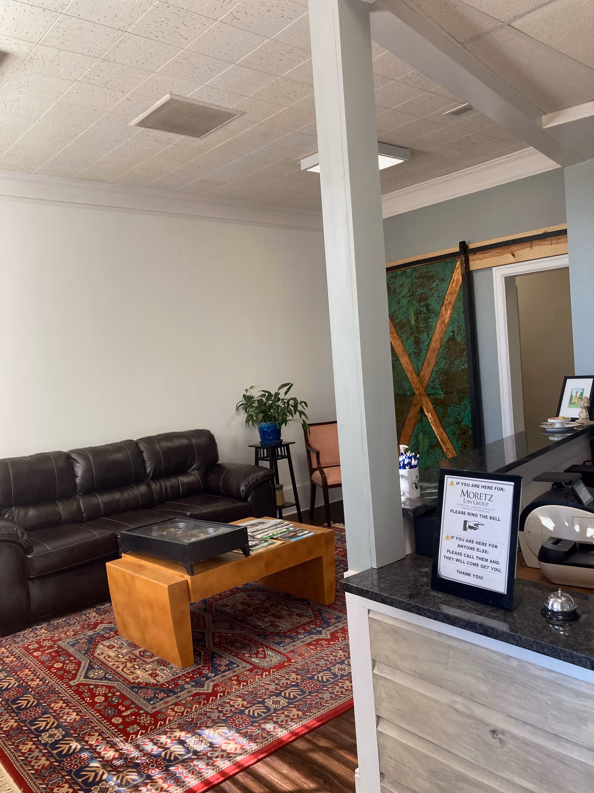 Lounge area of a senior facility with leather sofa, coffee table, and reception desk.