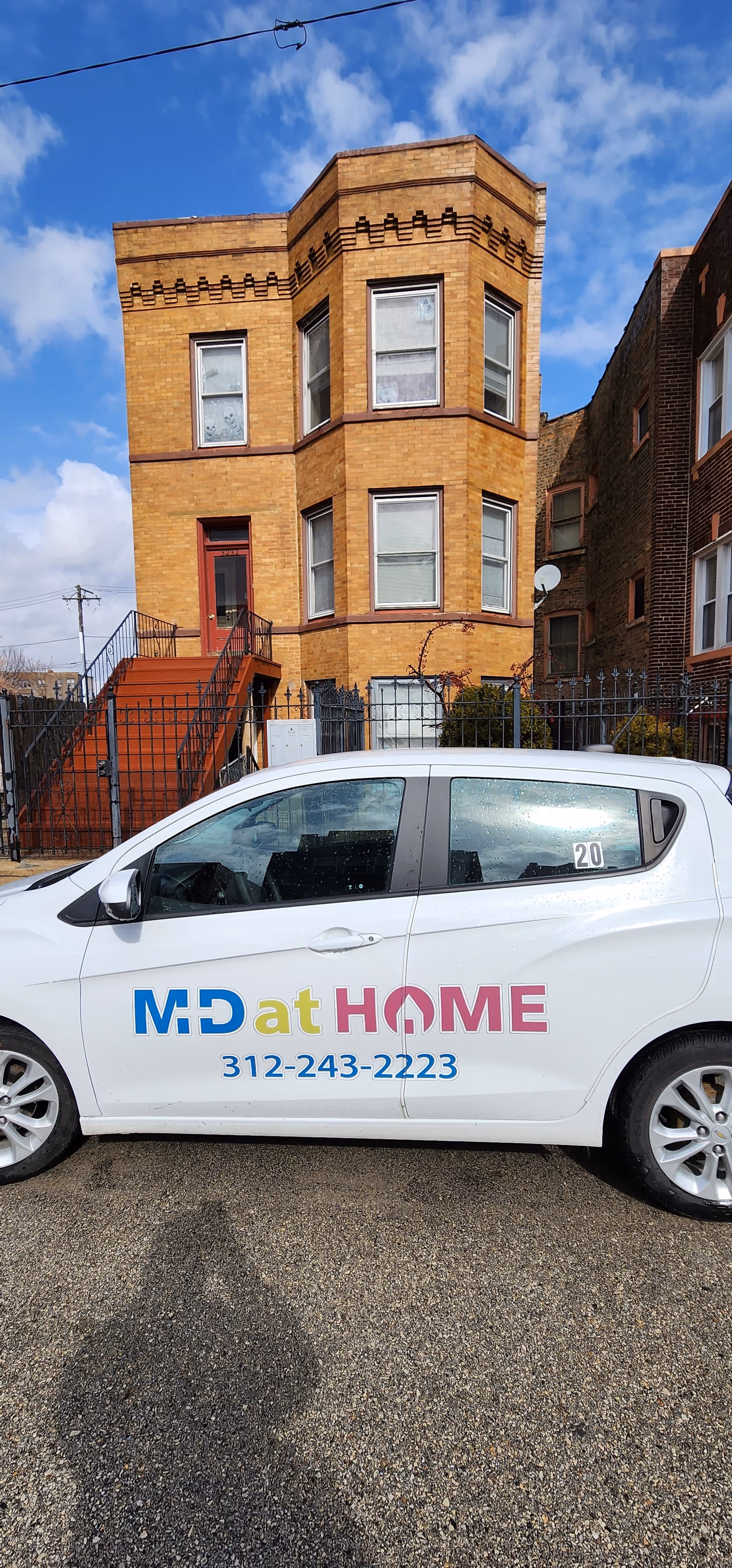 Brick building exterior with a parked MD at Home branded vehicle in foreground