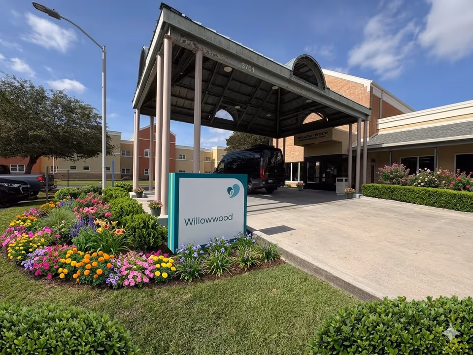 Exterior view of a senior living facility entrance with a covered canopy and flowers.