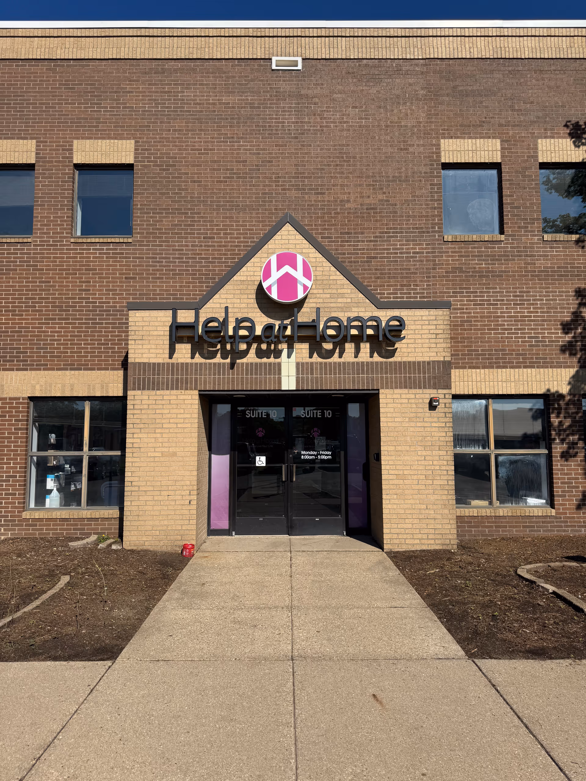 Brick building facade featuring Help at Home entrance with glass doors.
