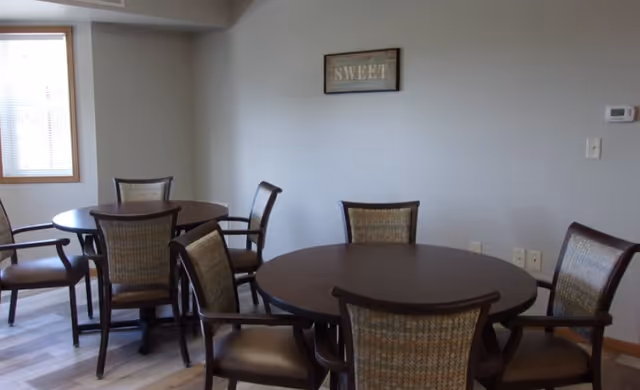 Interior dining area with round tables and cushioned chairs arranged in neutral tones.