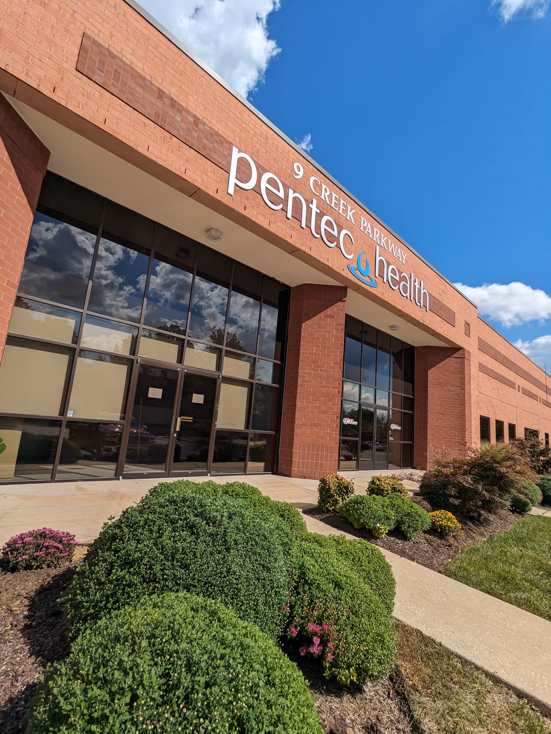 Exterior view of Pentec Health facility with brick facade and glass entrance.