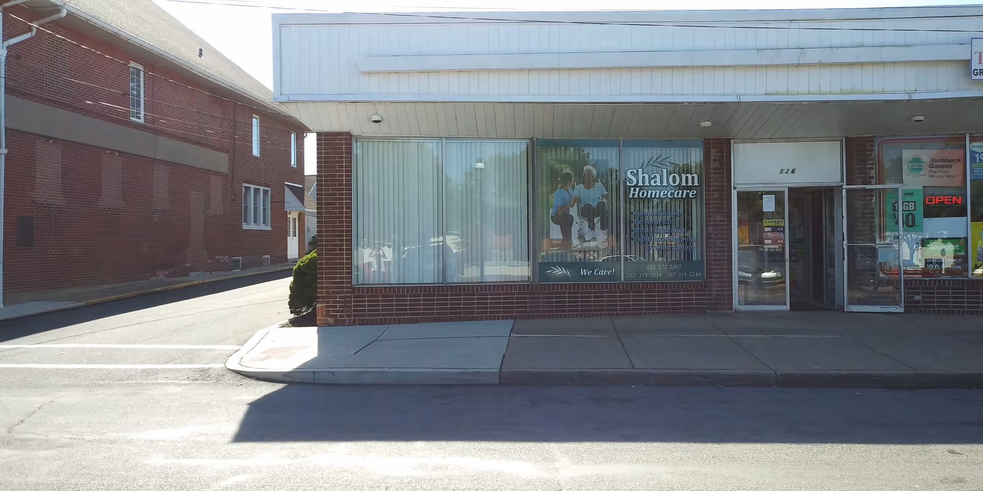 A brick storefront with large glass windows displaying Shalom Homecare signage.