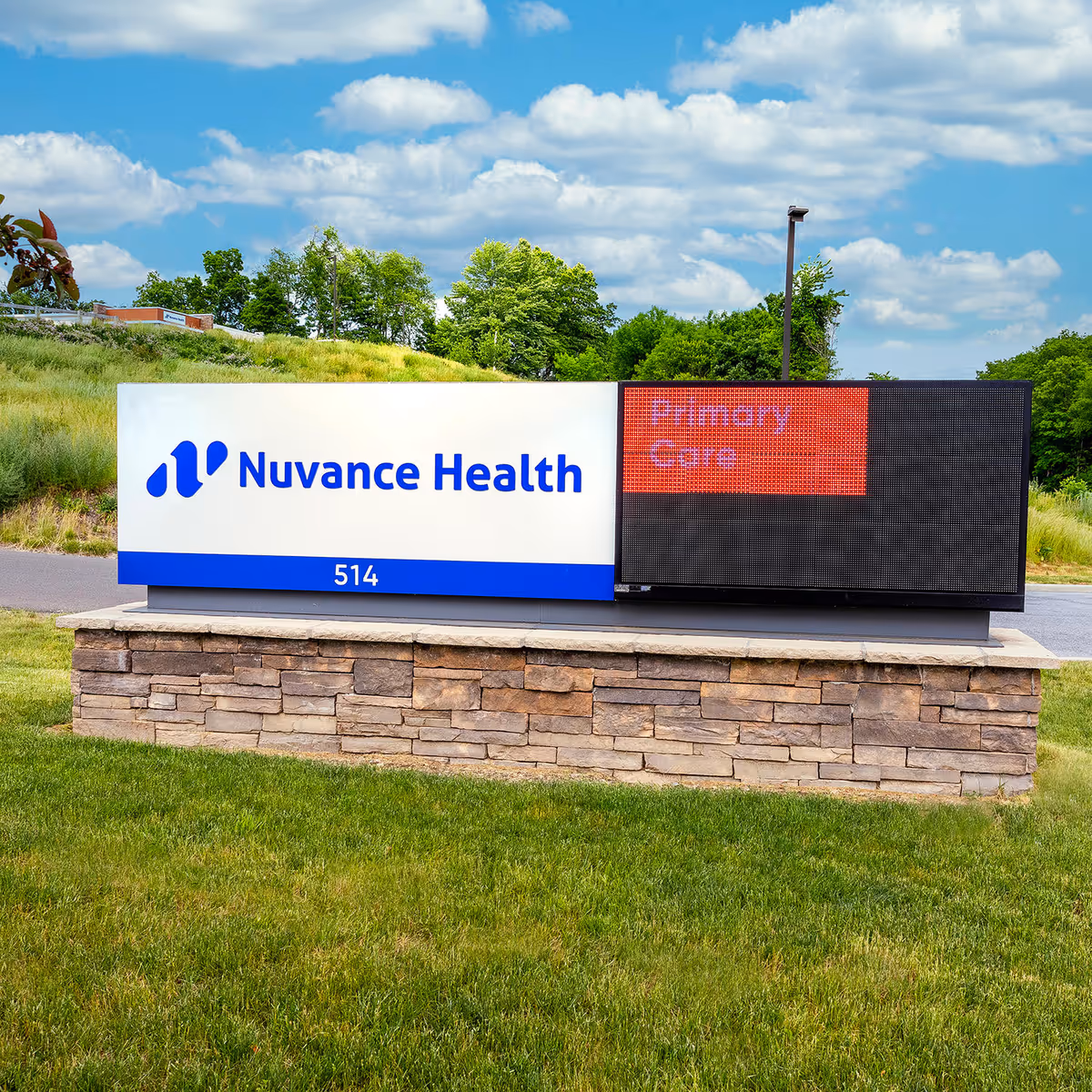 Outdoor sign reads Nuvance Health with digital display showing Emergency Care on a stone pedestal