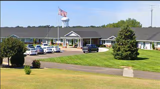 Exterior view of Kinship Pointe at McCook with parking lot and American flag.
