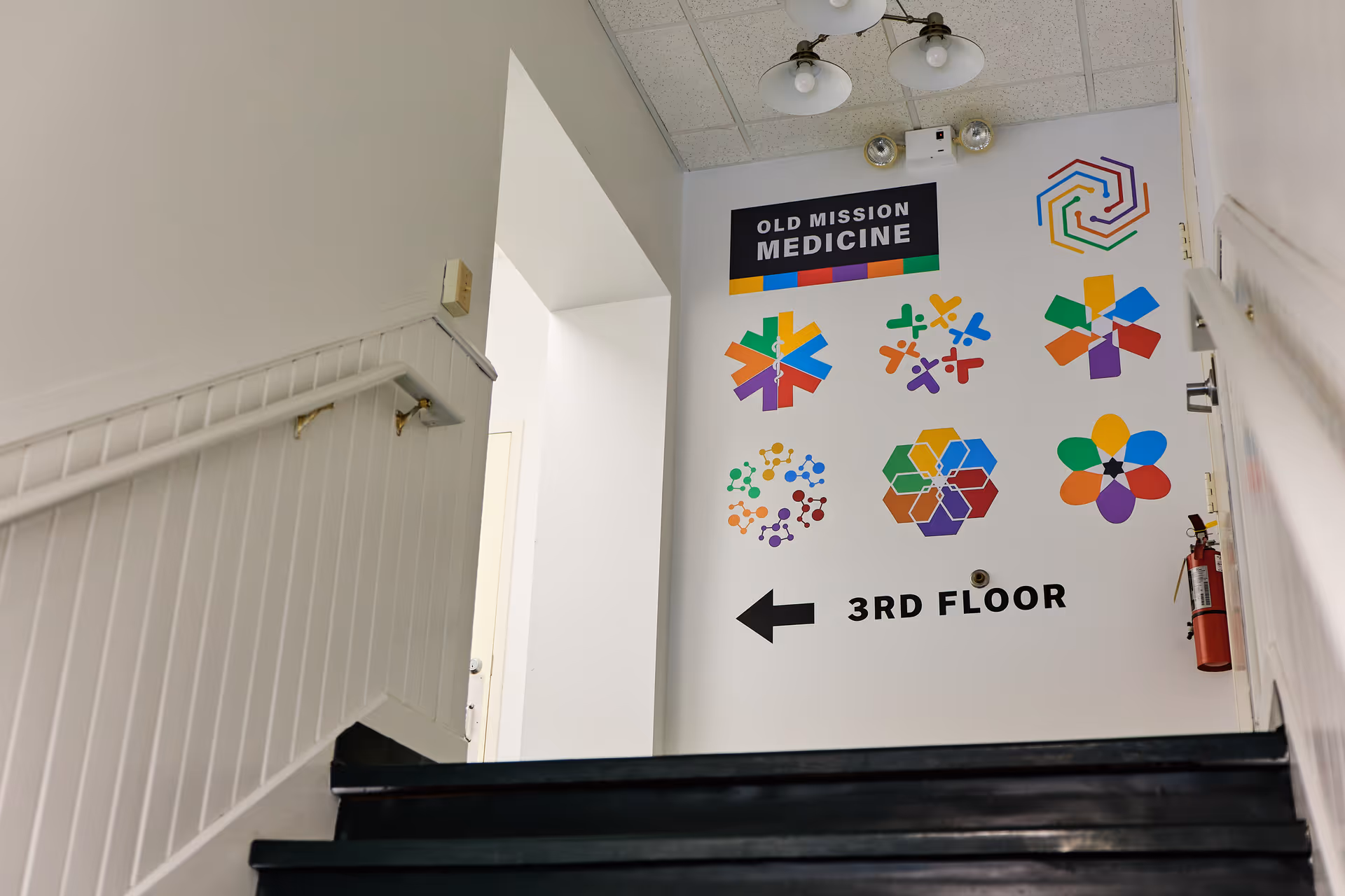Interior stairwell featuring Old Mission Medicine sign and colorful geometric decals, pointing toward the 3rd floor.