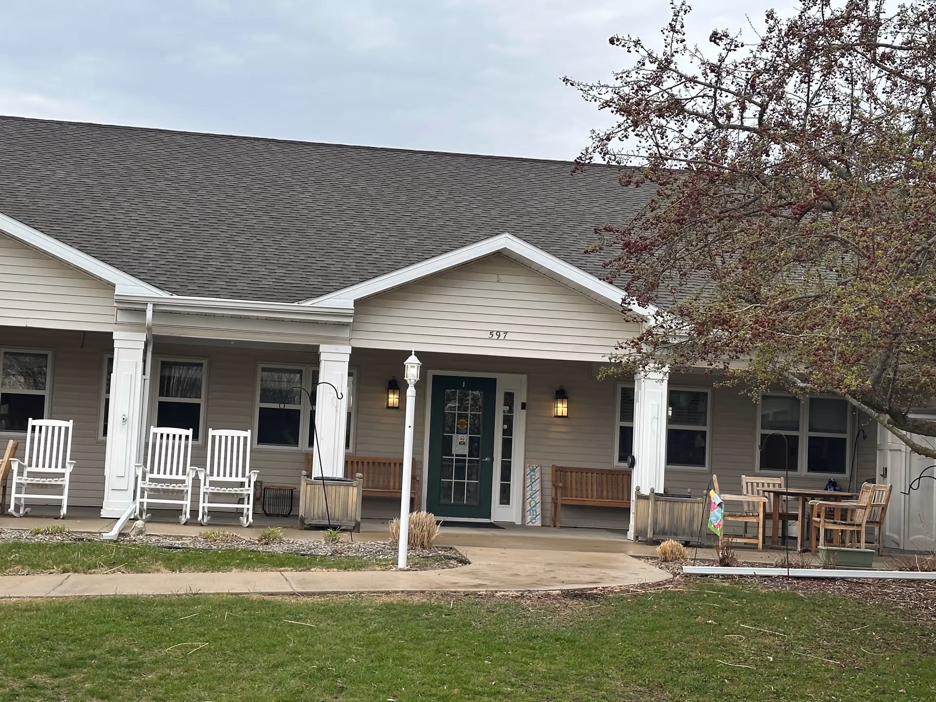 A single-story senior living facility exterior with a front porch and outdoor seating.