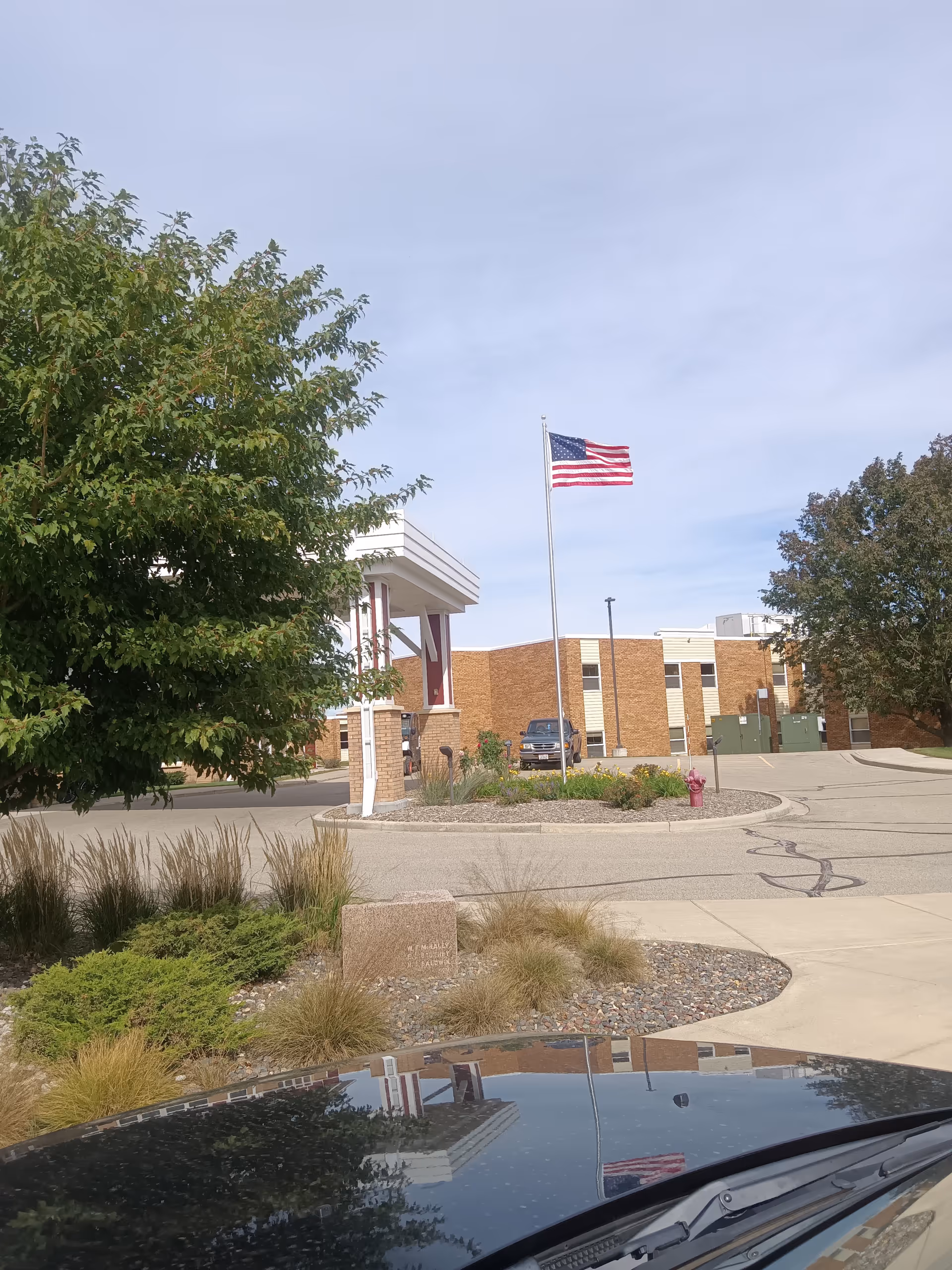 Front exterior of Kitty Rhoades Memorial Memory Care Center with American flag and landscaping.