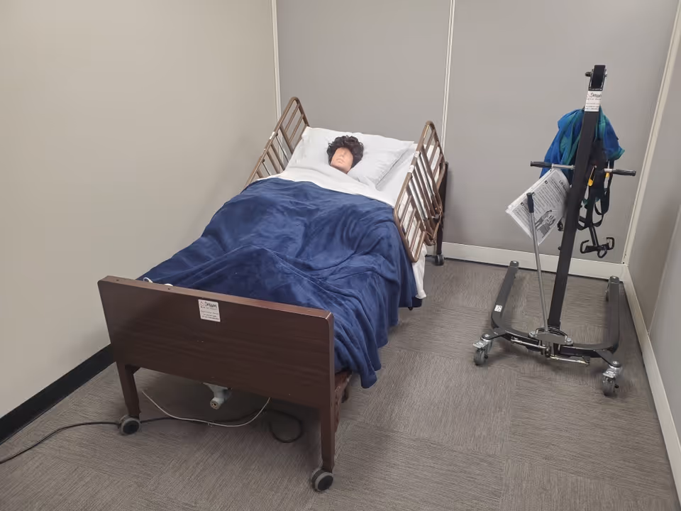 A hospital-style bed in a small senior care room with a patient lift beside it.