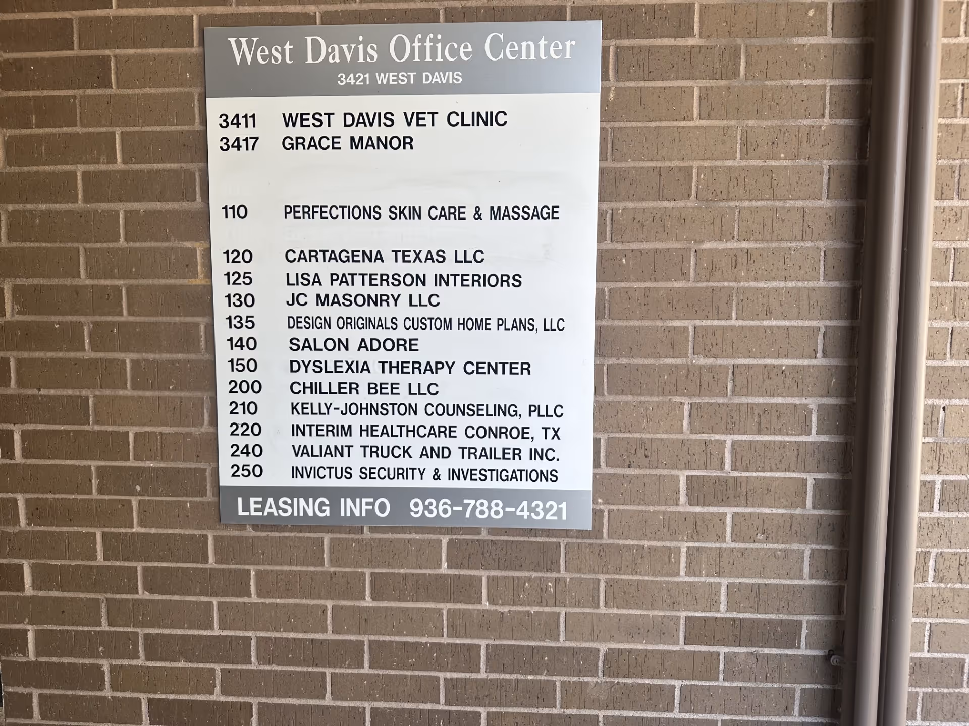 A brick exterior wall with a large directory sign listing offices, including Interim HealthCare Conroe.