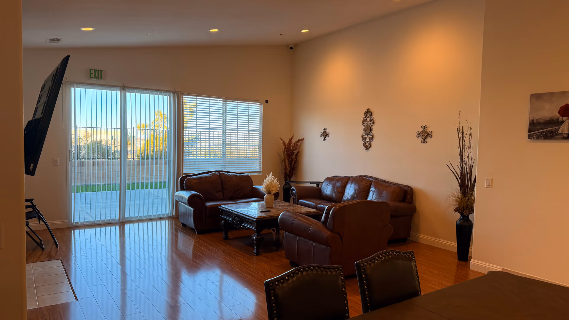 Sunlit senior living lounge with leather seating, coffee table, and patio door.