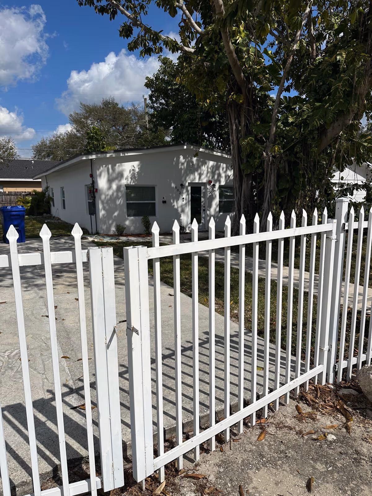 White, single-story assisted living building behind a tall white picket fence.