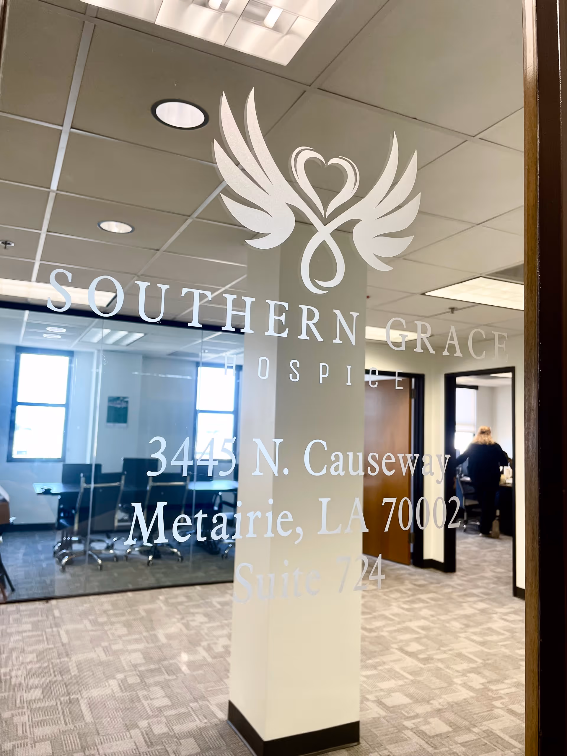 Glass office door displays Southern Grace Hospice logo and address inside a conference area.