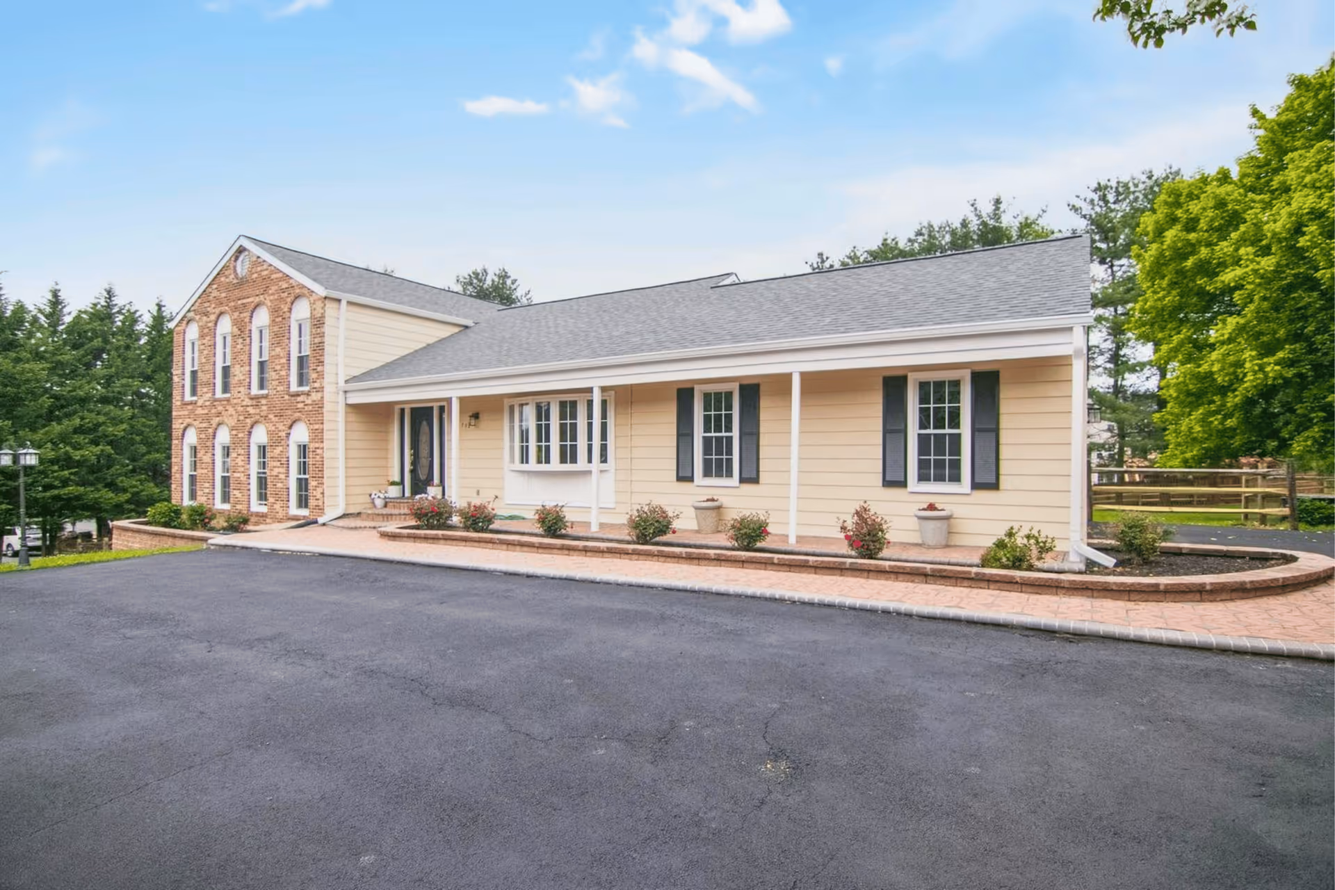 Front exterior of Gem Assisted Living: beige siding, brick accent, and paved entrance.