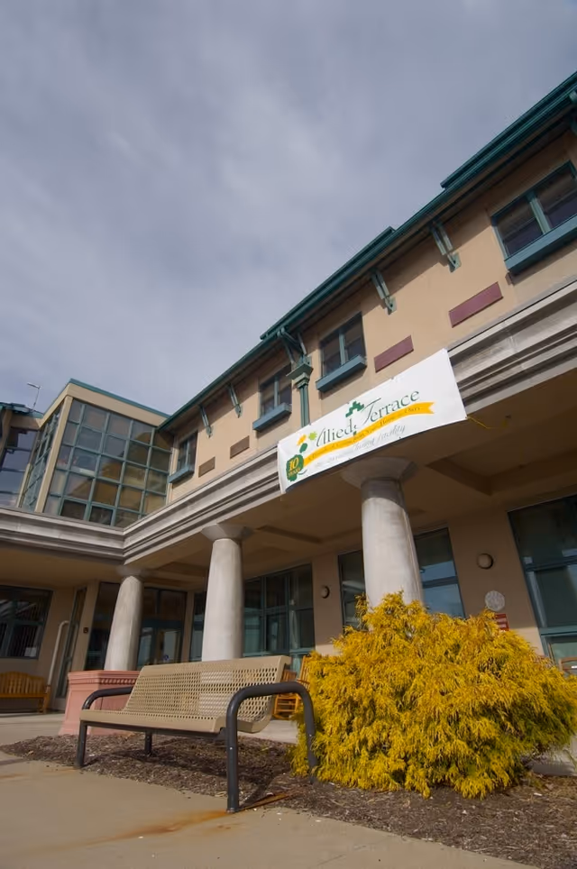 Exterior view of Personal Care at Allied Terrace with bench and banner.
