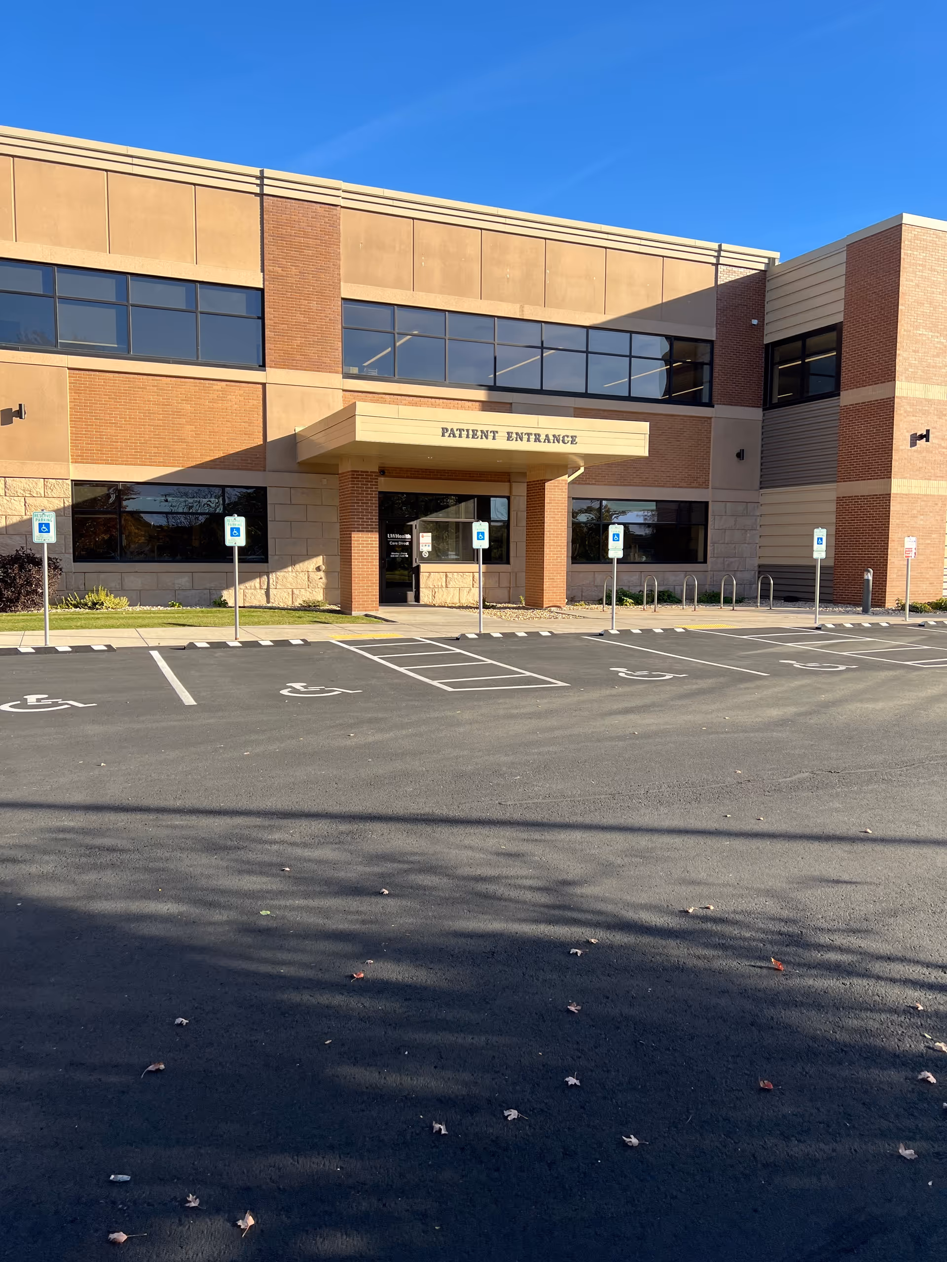 Exterior view of a brick health facility with patient entrance and accessible parking spaces.