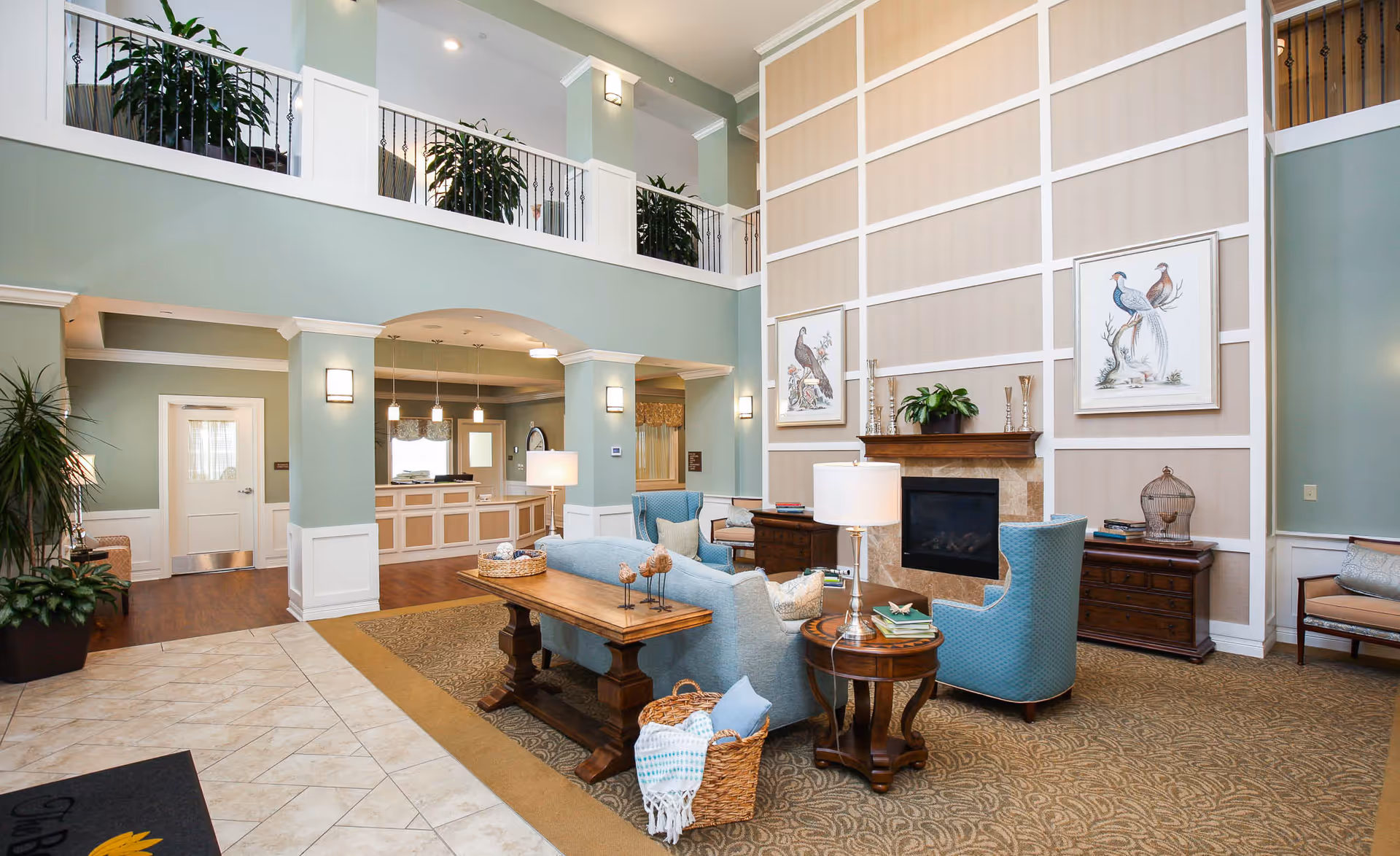 Bright senior living lobby with pastel walls, fireplace, and blue seating.