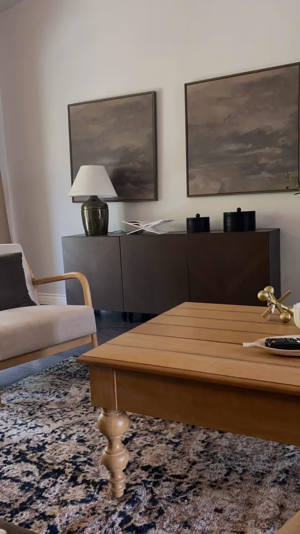 Cozy living room with wooden coffee table, sofa, cabinet, lamp, and artwork.