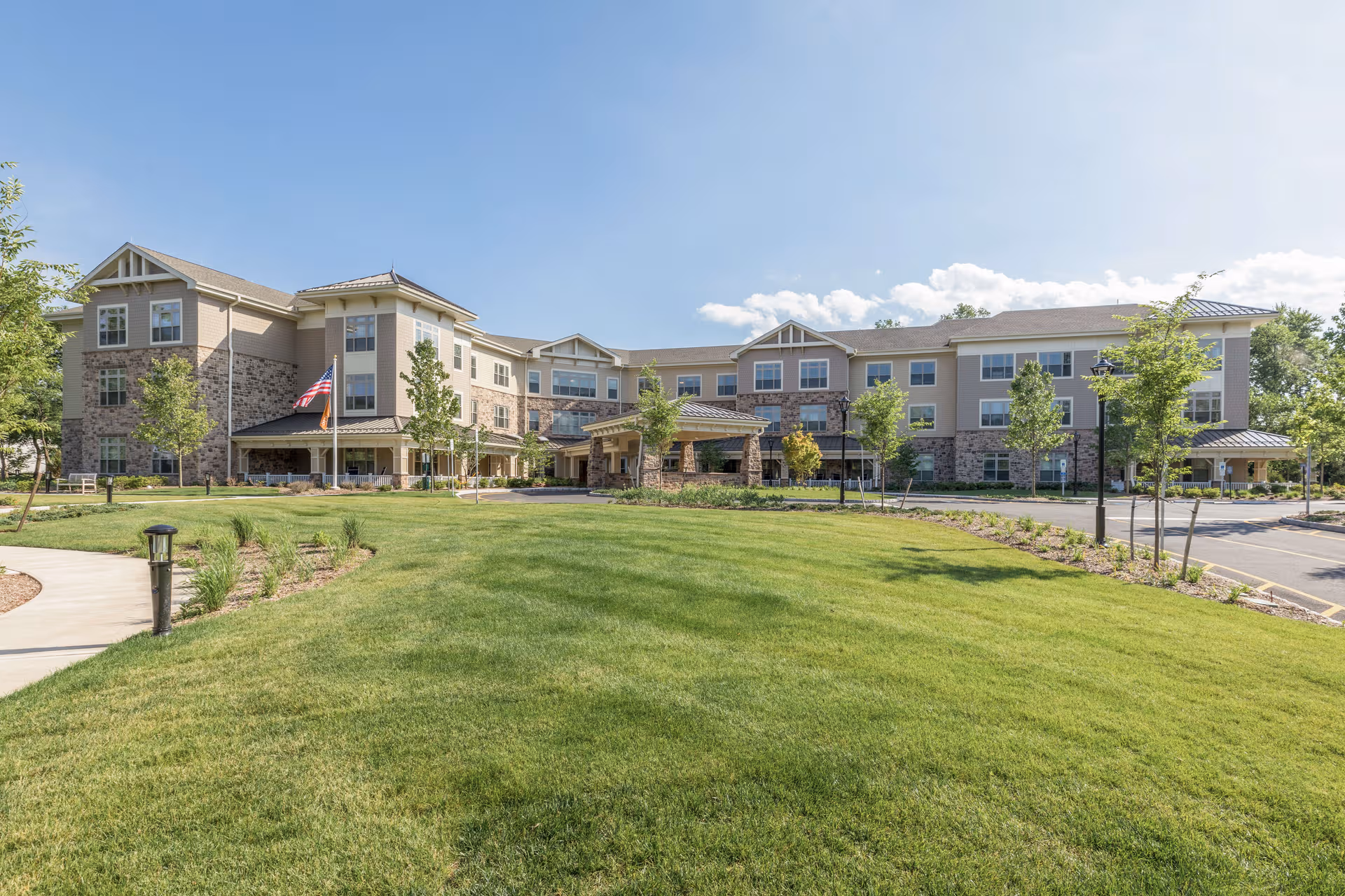 Sunrise of Bridgewater exterior: a multi-story building with stone accents and green lawn.