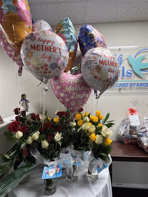 Indoor display of Mother's Day balloons and flowers on a table inside a senior care facility.