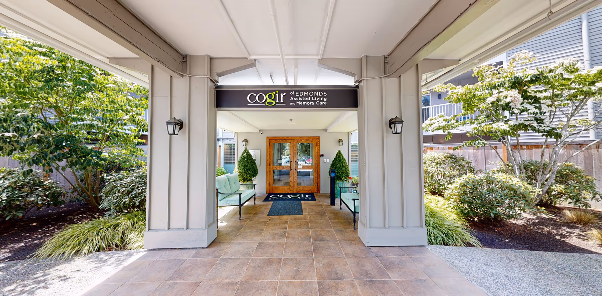 Entrance to an assisted living facility with a covered walkway and glass doors.