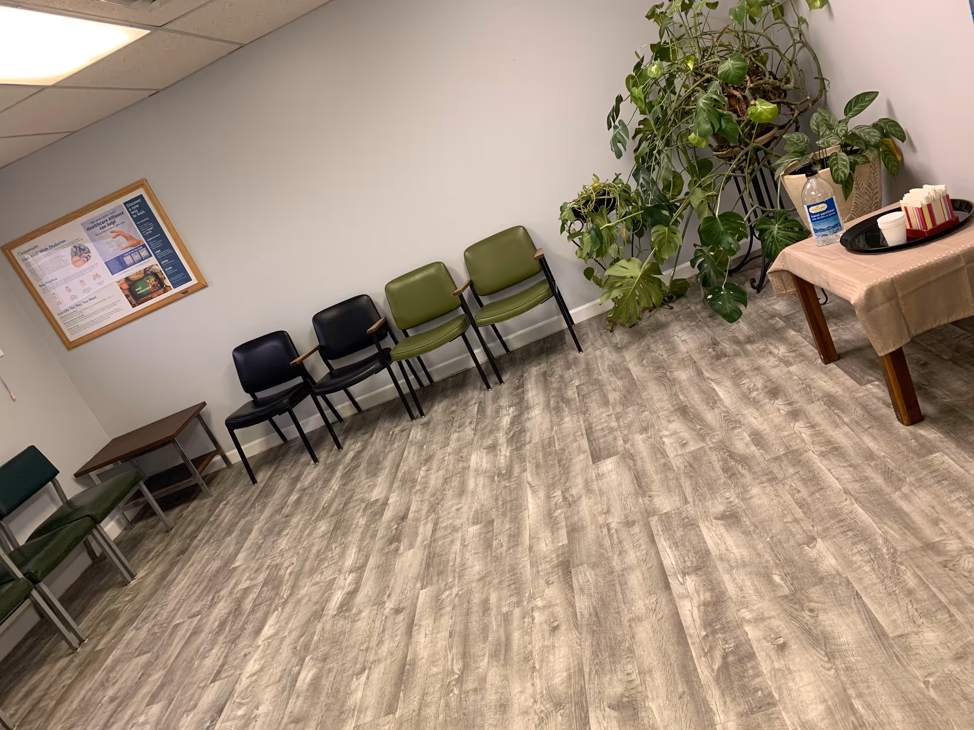 Waiting area with chairs, a potted plant, bulletin board, and service table.