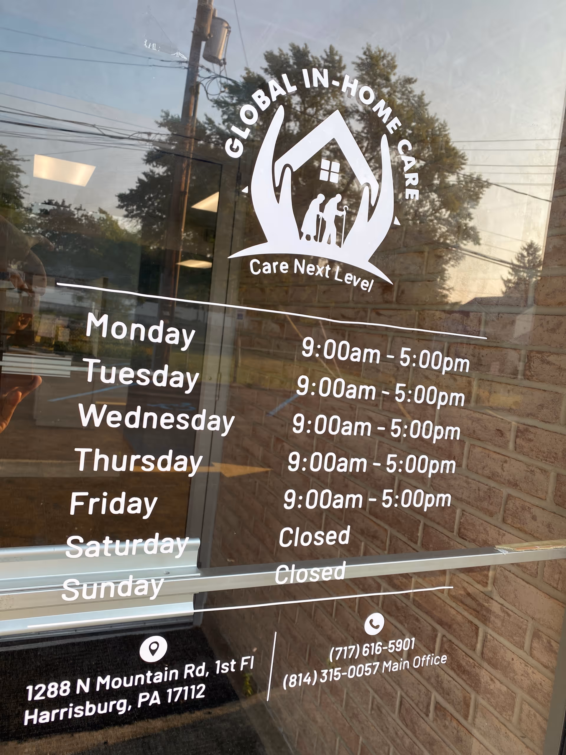 Glass door with Global In-Home Care logo, hours, and address reflected in window.