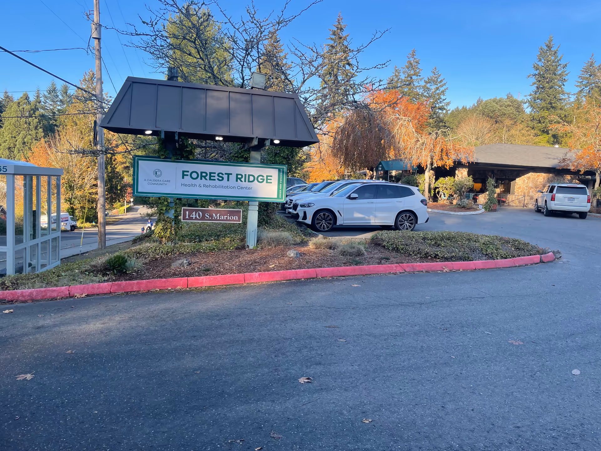 Exterior of Forest Ridge Health and Rehabilitation Center with sign, parking lot, and trees.