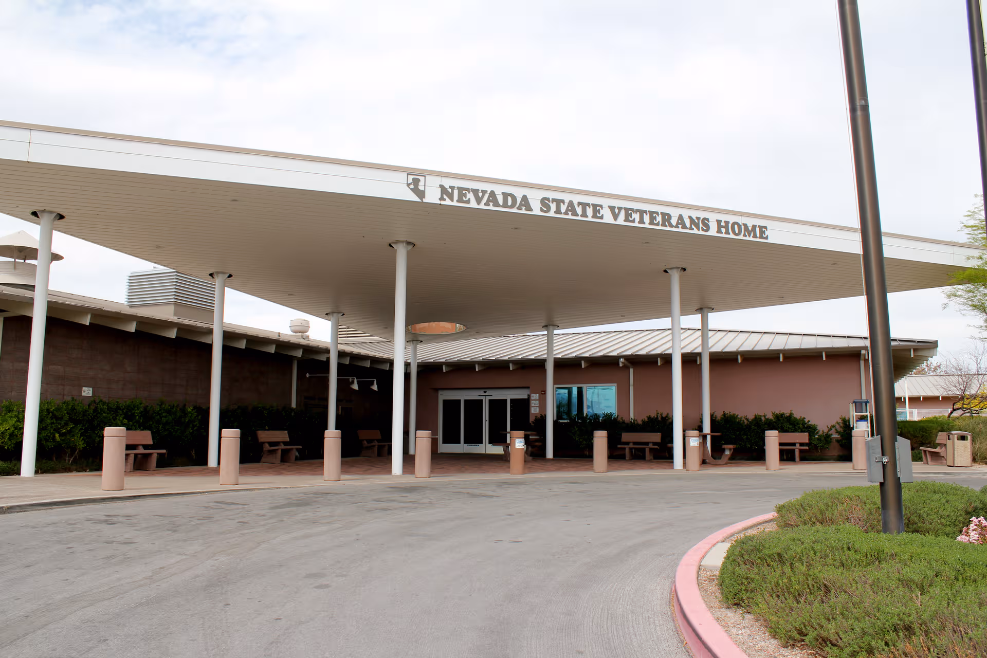 Front entrance of Nevada State Veterans Home with canopy, pillars, and benches.