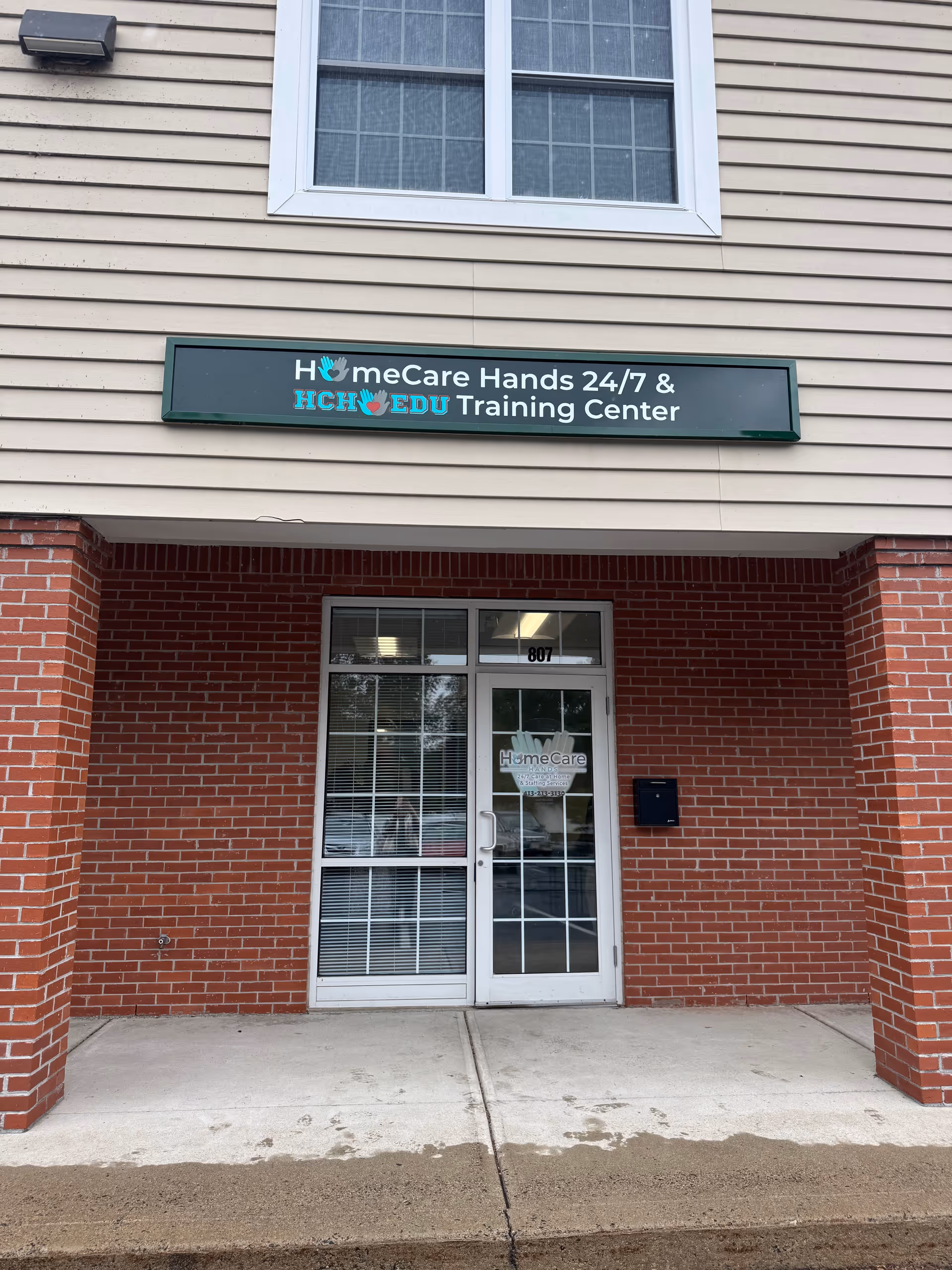 Exterior view of a brick building entrance with a HomeCare Hands Training Center sign.