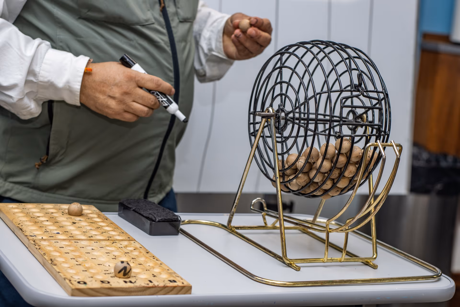 Person's hands cue a bingo game with a rotating cage and bingo card.