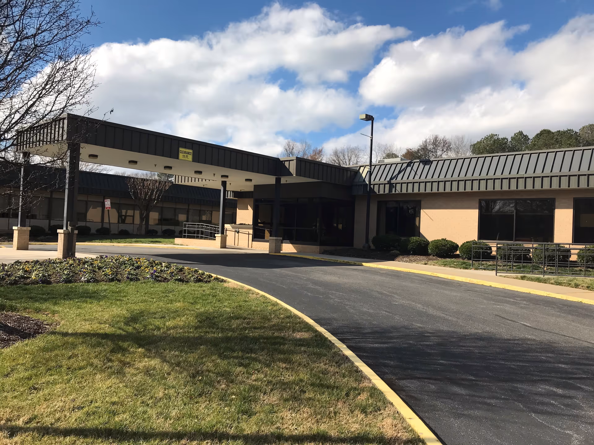 Exterior view of Lexington Court senior living facility entrance with driveway and landscaping.