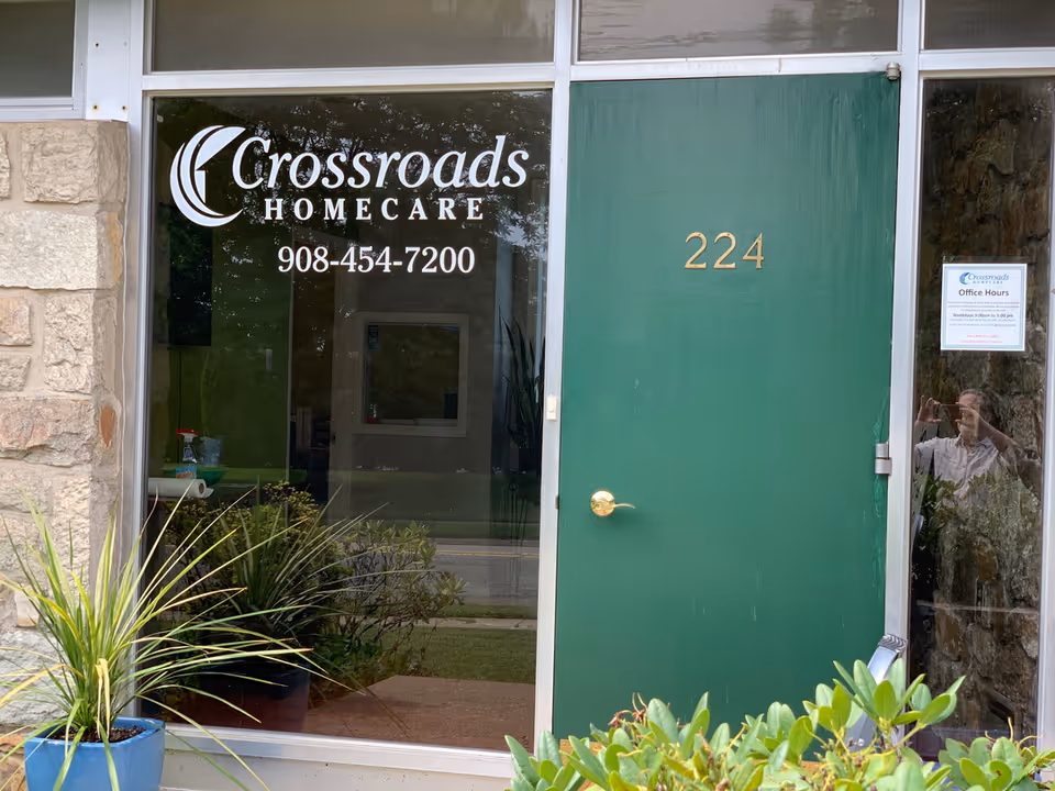 Glass storefront of Crossroads Homecare with green door 224 and plants.