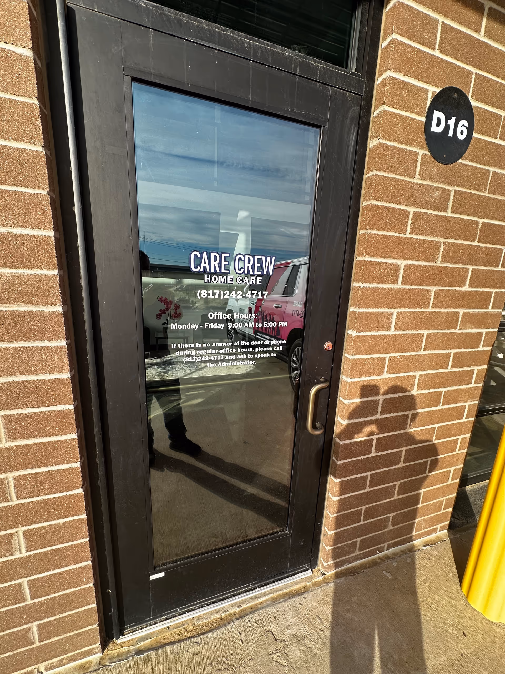 Glass door with Care Crew Home Care signage, brick exterior and a D16 plaque.