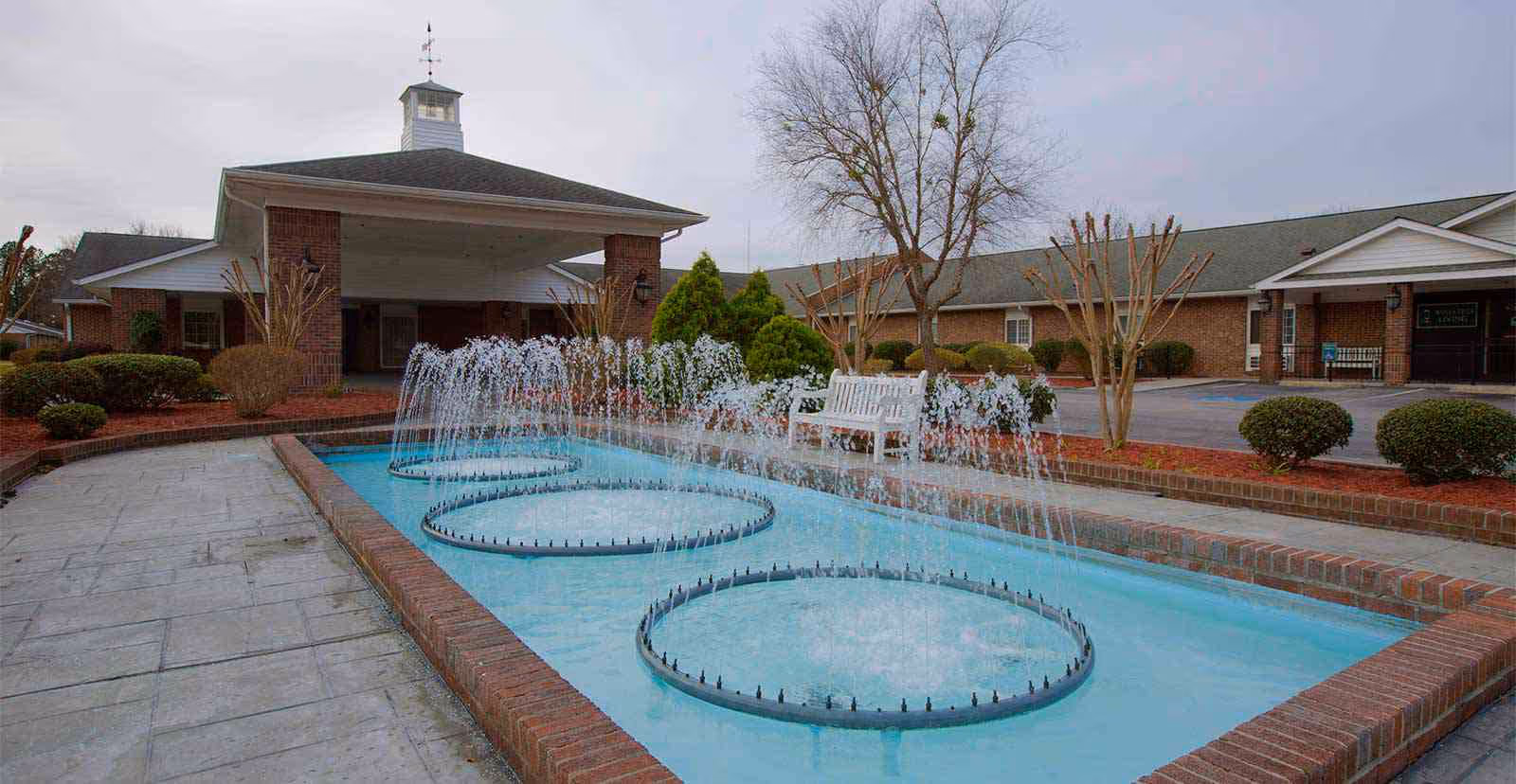Exterior view of Truewood by Merrill New Bern featuring a brick courtyard fountain