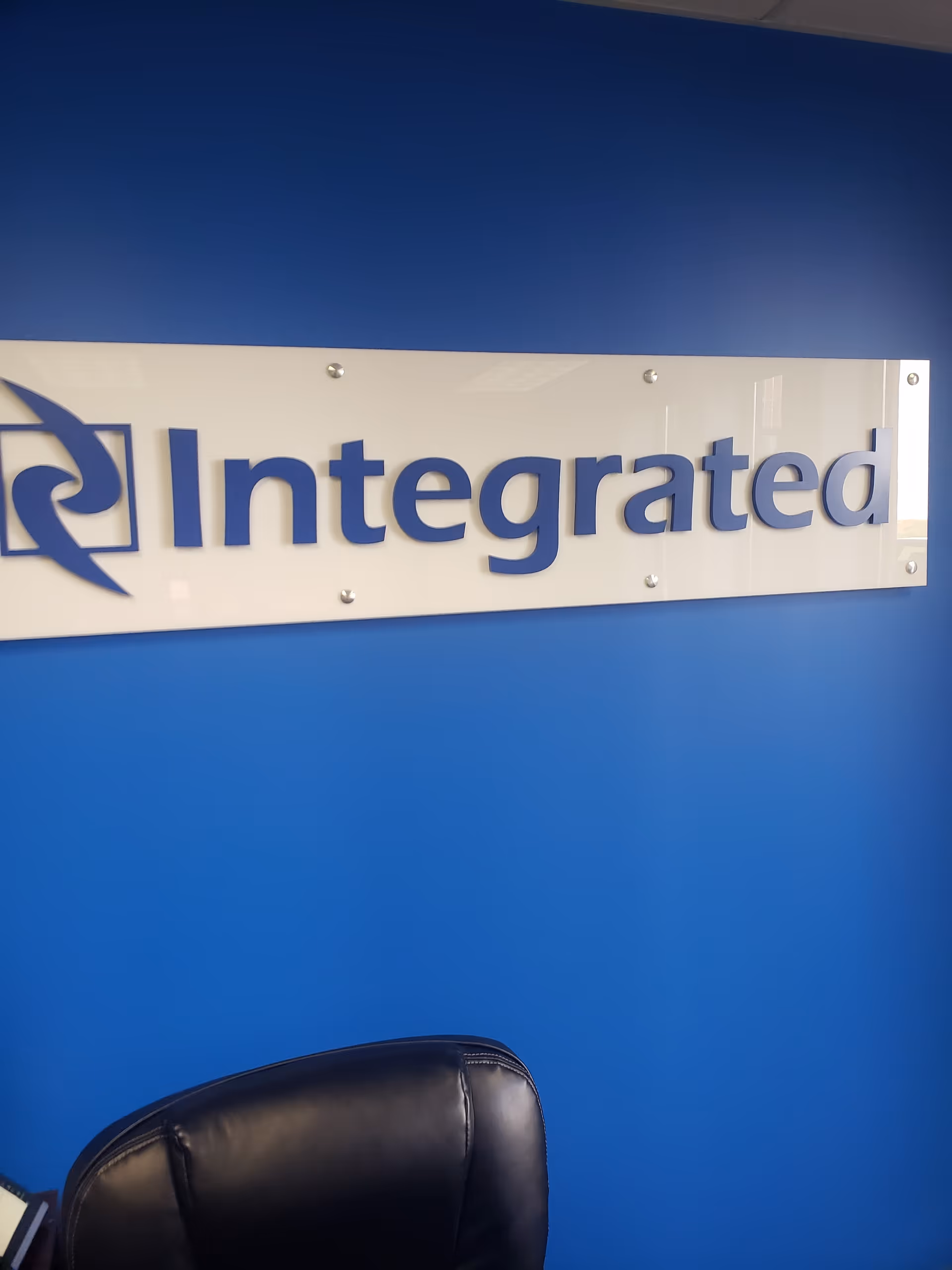 Blue interior wall with a glass sign reading Integrated and a black leather chair.