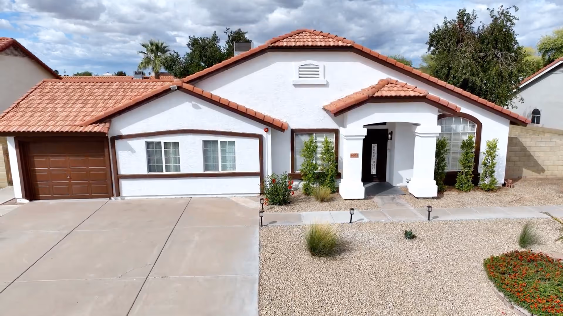 Front view of a white stucco building with red tile roof and desert landscaping.