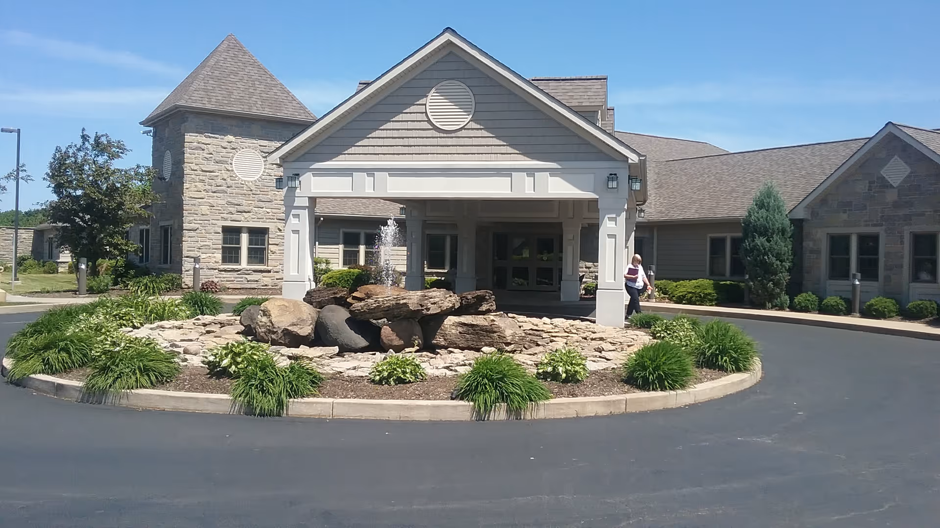 Exterior view of Niagara Hospice facility with circular driveway, entrance, and rock fountain
