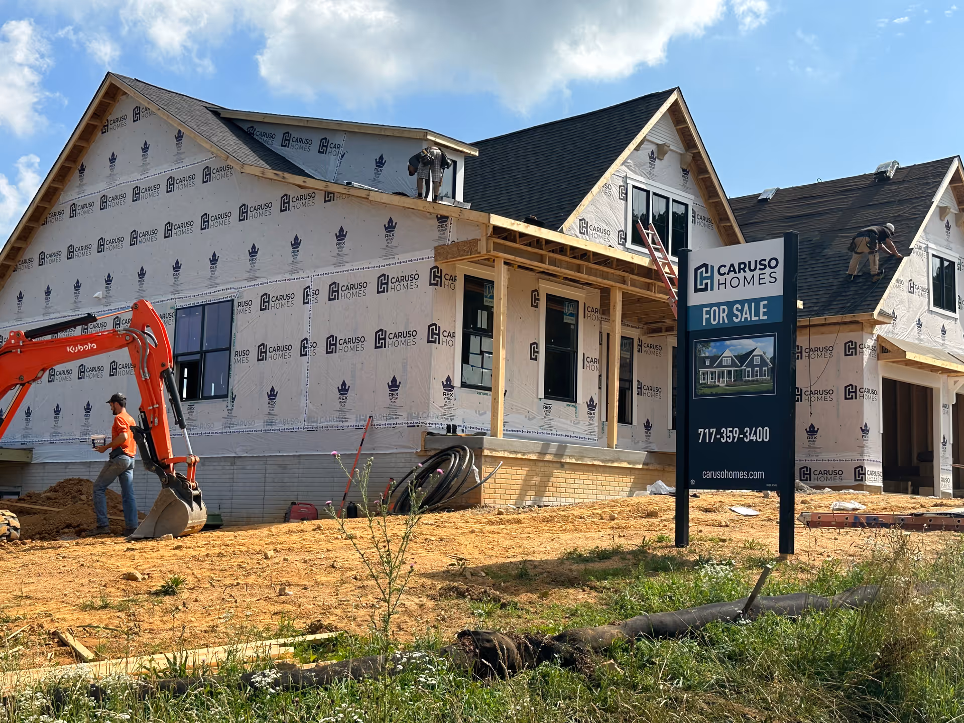 Under-construction house exterior with two workers and a For Sale sign.