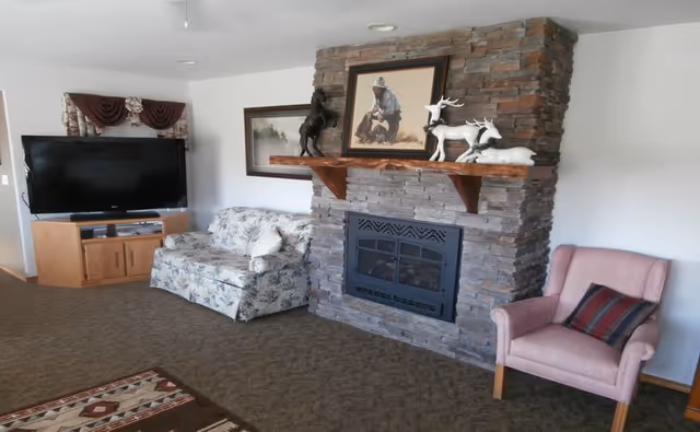 Cozy living room with stone fireplace, seating, and a television.