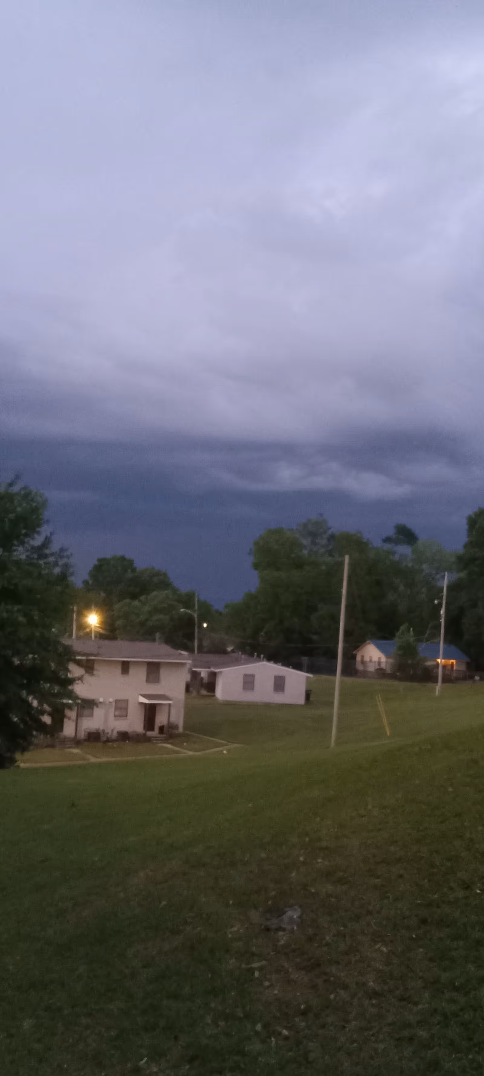 Overcast sky over a grassy hill with small housing buildings in a senior living complex.