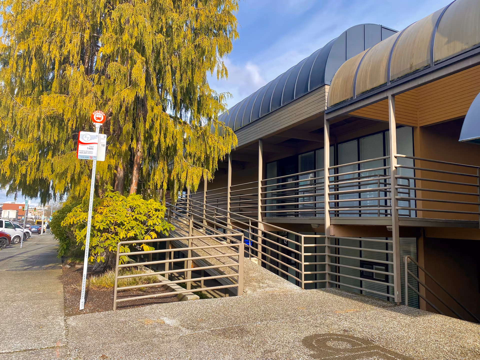 Exterior view of a multi-level senior living facility entrance with metal railings and stairs.