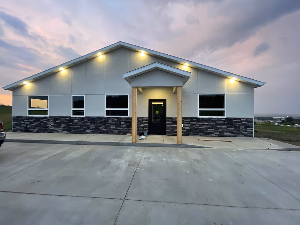 Exterior view of a newly built senior care facility with lit front entrance.