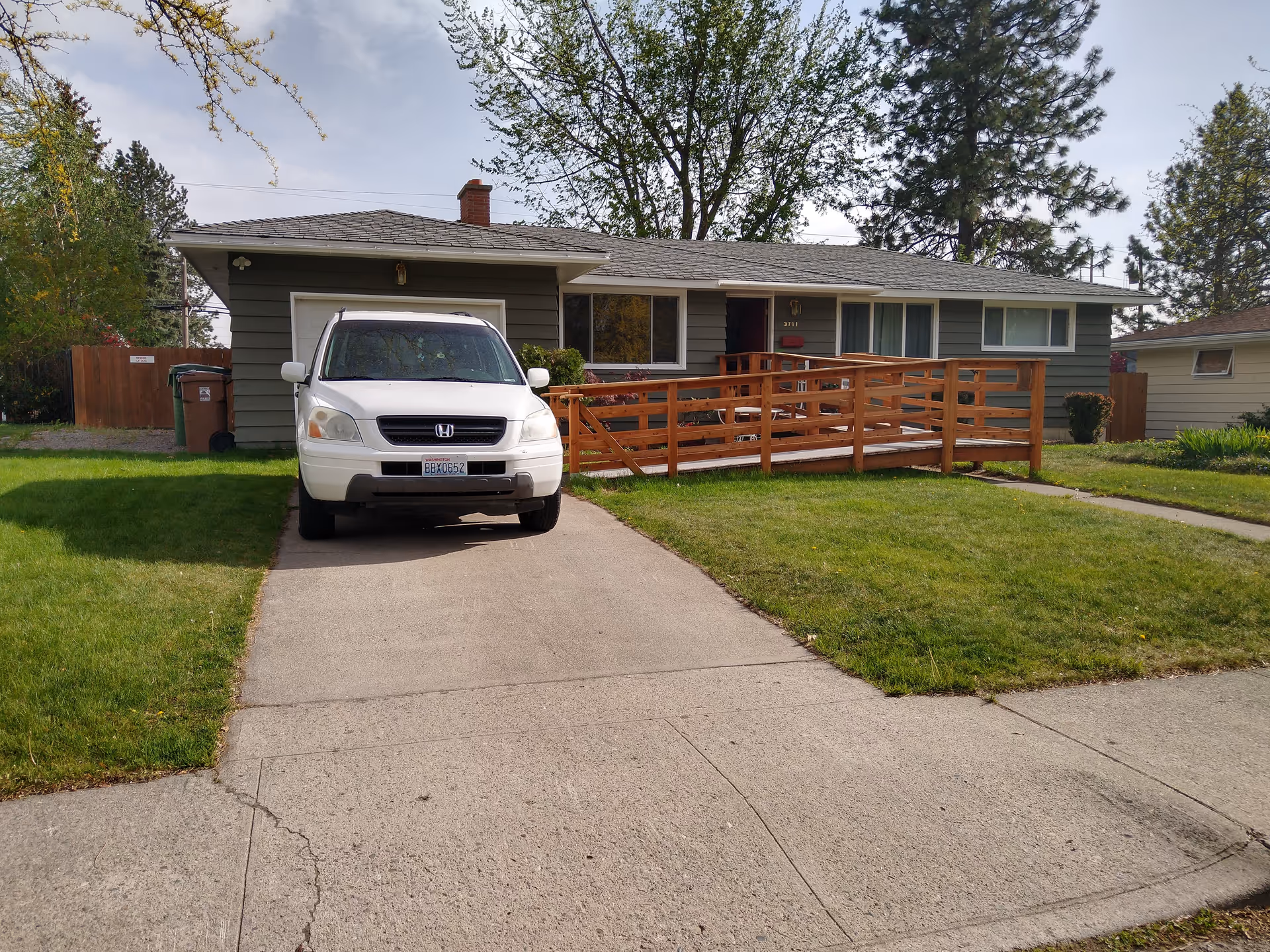 Single-story house with a wooden ramp and a white SUV parked on the driveway.